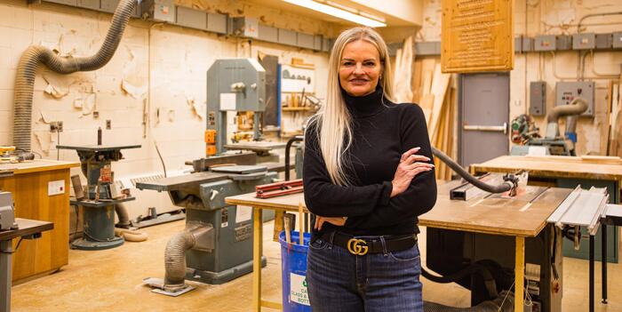Ena Holtermann stands with her arms crossed in a room with technological education equipment.
