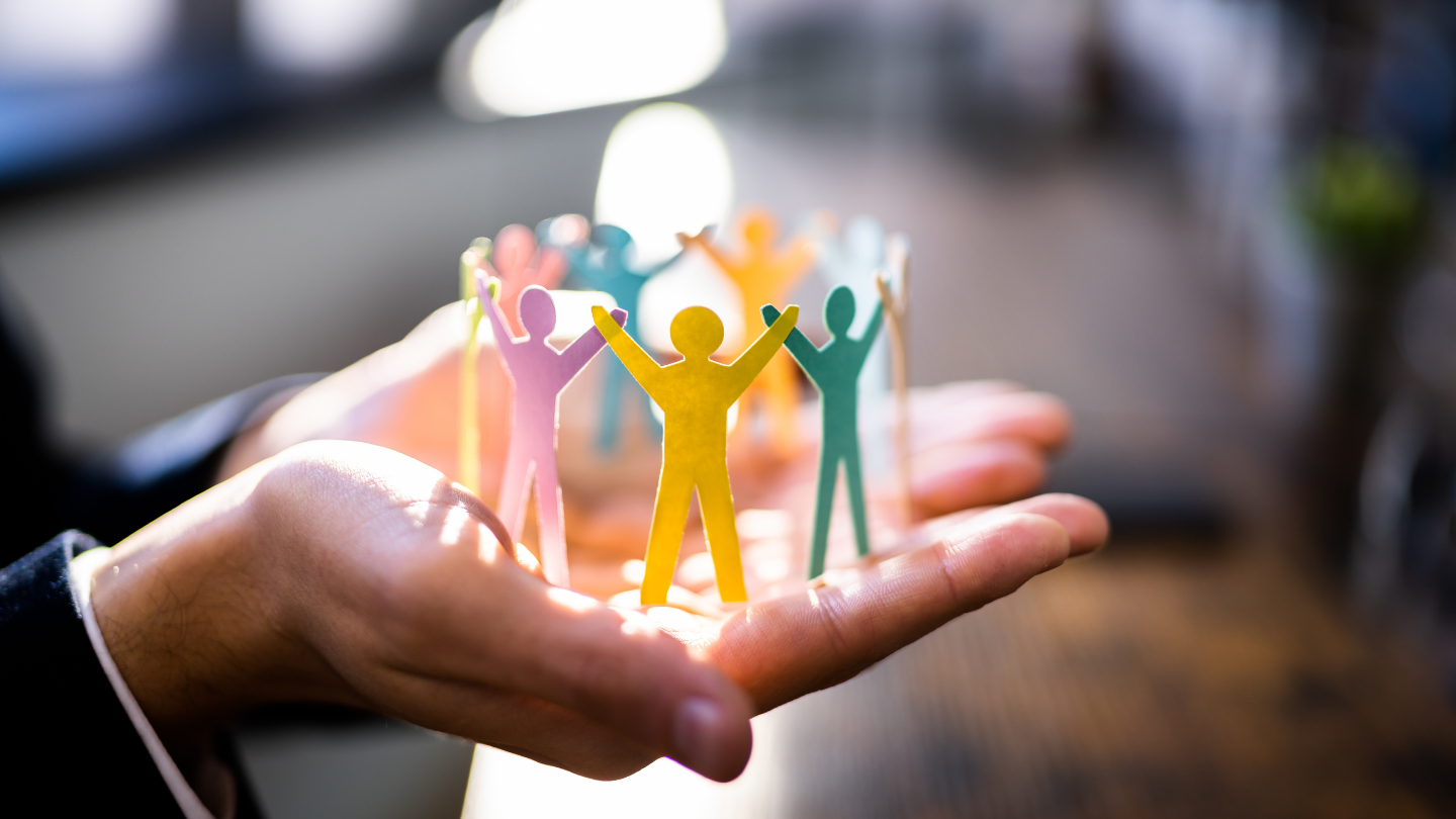 A person holding paper origami showing a group of people together
