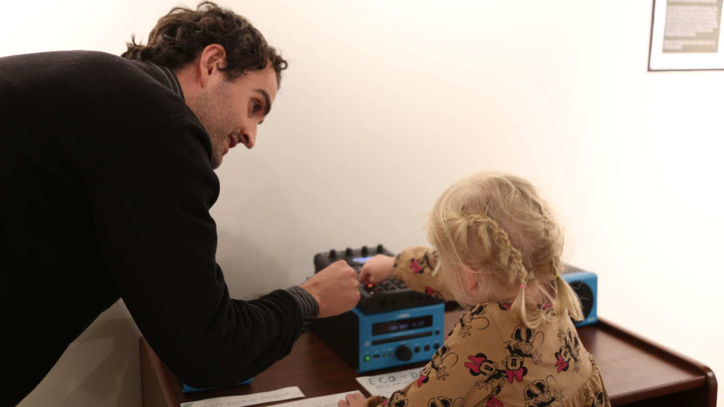 A man teaching a small child at a workstation