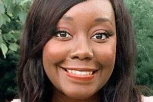 Nyasha smiles at the camera against a green background