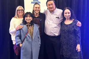 Several people smile at the camera in front of a sign that says Mayor's Arts Award