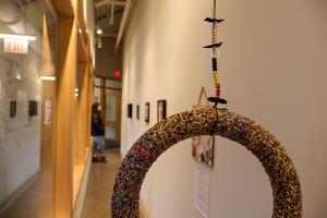 Art hanging in a gallery. Black, red, yellow and white beads form a circle