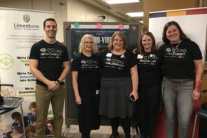 Five people smile at the camera. All are wearing black Neurovibes t-shirts