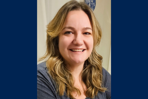 Anastasia Reid smiles inside wearing a grey shirt.