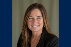 Jennifer McMaster smiles wearing a black shirt in front of a grey background.