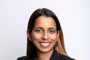 Melissa Carvalho smiles in front of a light grey background.