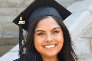 Jessica Dassanayake smiles wearing a graduation cap and gown.