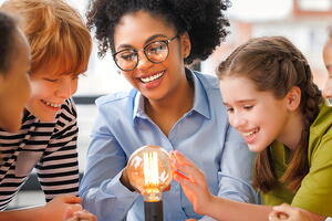 A teacher playing with a lightbulb with students