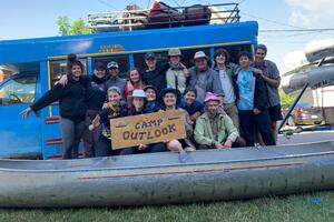Staff from Camp Outlook smile in a large canoe