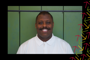 Mohamed Yusuf smiles in front of a green background. There is a black border around the photo with yellow, red, and green arrows overlayed on the right side.