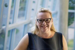 Dr. Kerstin Merz-Atalik stands in front of some windows smiling