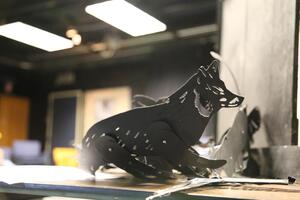 A black cutout puppet that is a wolf sitting on a table.