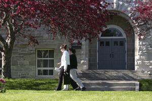 Two people walk outside of a building with trees in spring.
