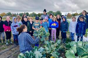 Emily Duncan displays a large harvested vegetable to a group of students.