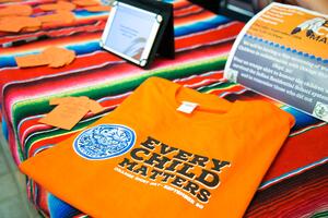 An orange shirt that says "Every Child Matters" sits on a table