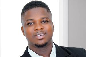 David Baidoo-Anu poses in a suit jacket in front of a window.