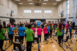 Sistema Kingston students perform with their backs facing the camera as they face their parents in the audience.