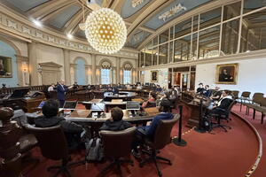 An image of Kingston City Hall with tables and chairs and a fancy orb like chandalier