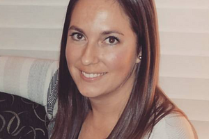 Laura smiling at camera while sitting with a sweater on 