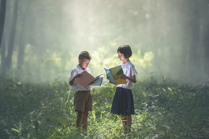 Two children reading books in nature