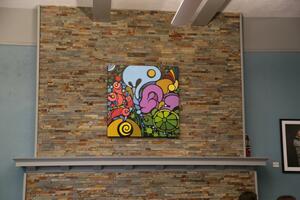 A colourful mural hangs above a large stone fireplace