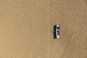 A boat with paddles on the surface of a desert