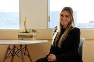 A white woman with blond hair smiling at the camera in an office