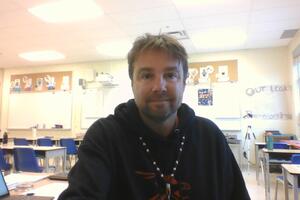 A man smiles in a classroom 