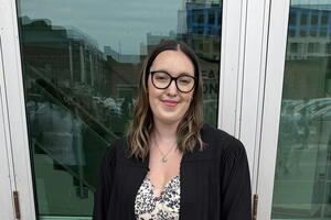 A woman is a graduation robe wearing glasses