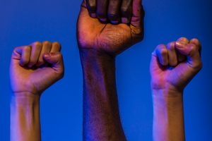Three fists in the air with a dark blue background