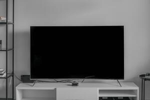 A tv sits on a white stand against a white wall. The screen is blank.