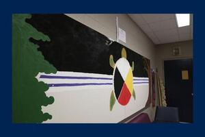 A mural painting of a turtle with a medicine wheel on its back.