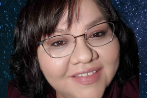 Samantha Doxtator smiles at the camera with a blue galaxy background behind her