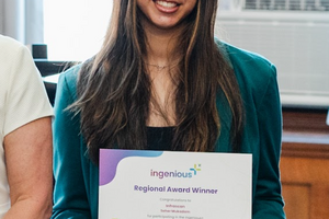 Seher Mukadam smiling at the camera holding a 'Regional Award Winner' certificate
