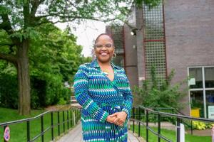 A woman wearing a vibrant blue white green and white dress smiles for the camera