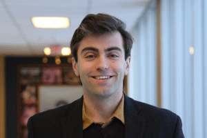 Nathan Rickey smiles in a hallway.