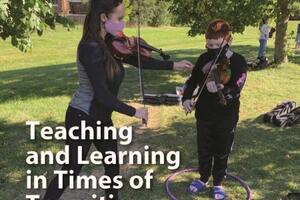 A teacher playing an instrument while masked outside with a student who is also masked