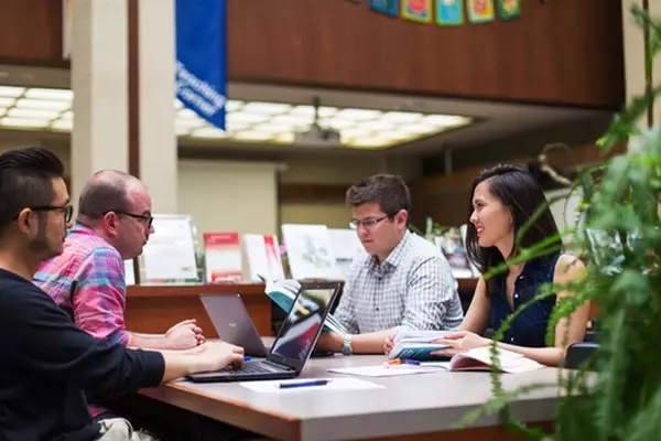 Group of individuals at a table working. Opens to past conferences page.