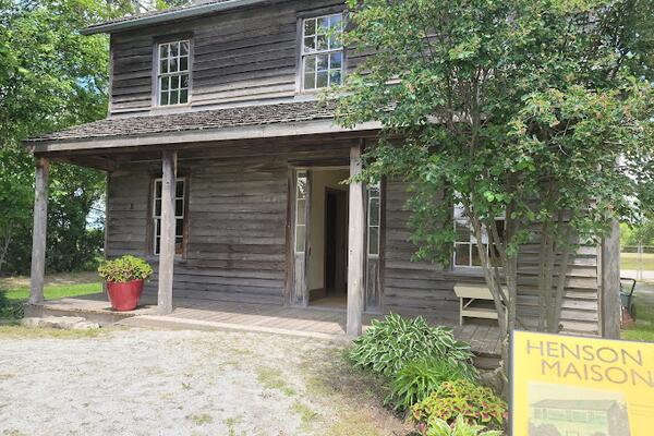A wood two story old building with a tree in front