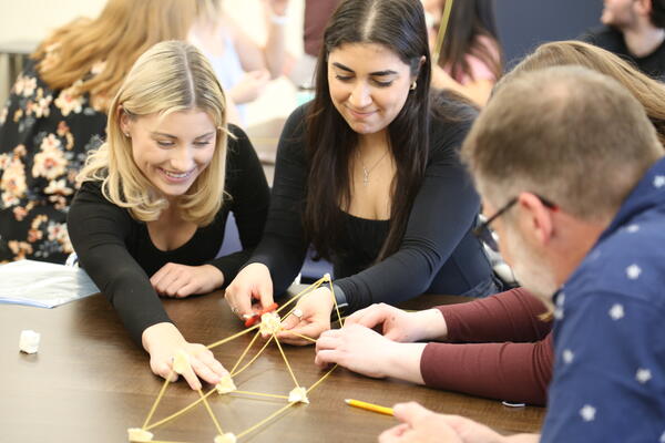 A group of four students constructing a bridge out of pasta