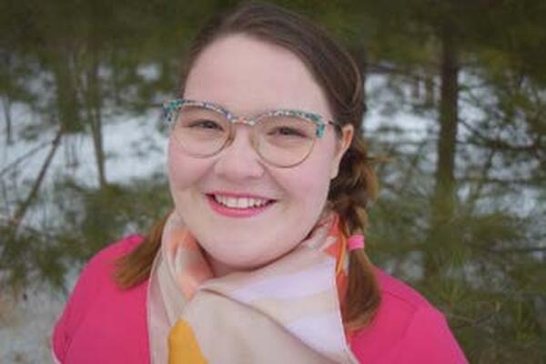 Portia Chapman smiles wearing glasses and a scarf.