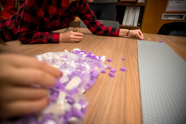 White and purple legos sit in a pile on a table.