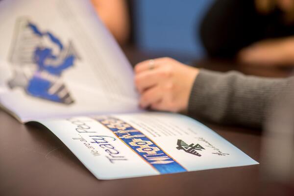 A person holds the centre of a book, it is open to a page that reads "We are all Treaty People."