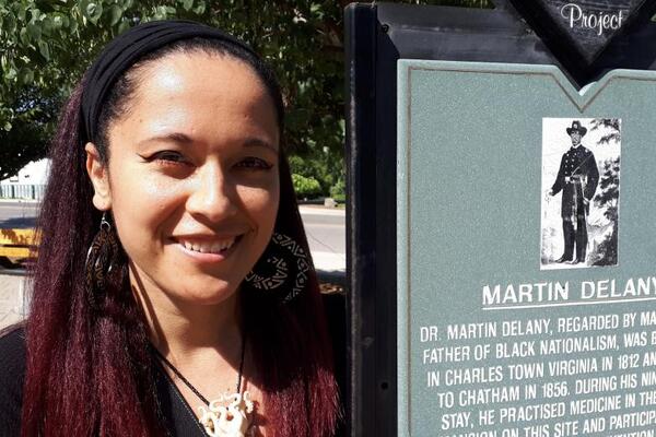 Deirdre McCorkindale smiles next to a plaque.