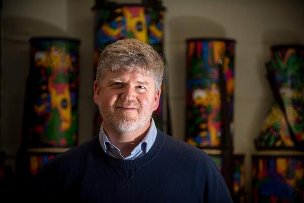 Ben Bolden smiles in front of four colourful patterned pillars.