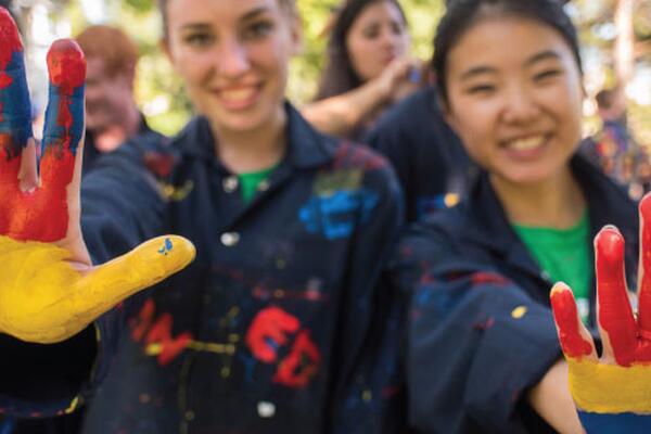 two students with hands up with tricolour paint on their hands