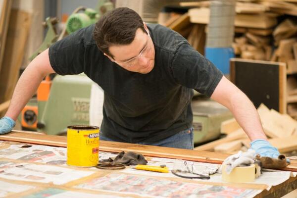 A person staining a piece of wood in a shop 