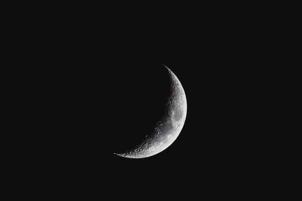 A moon in a half sliver in the night sky.