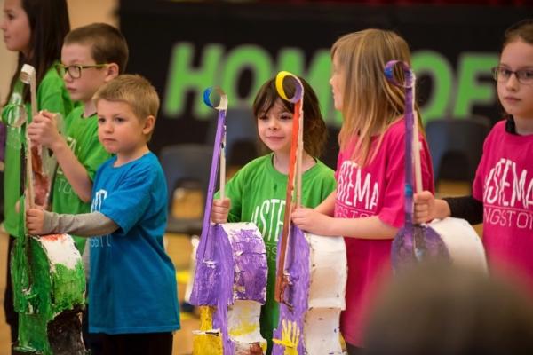 sistema students holding paper violins