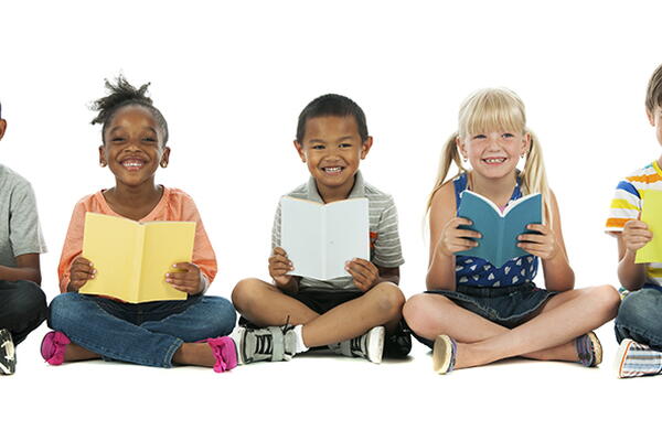 a group of kids holding a book smiling at the camera
